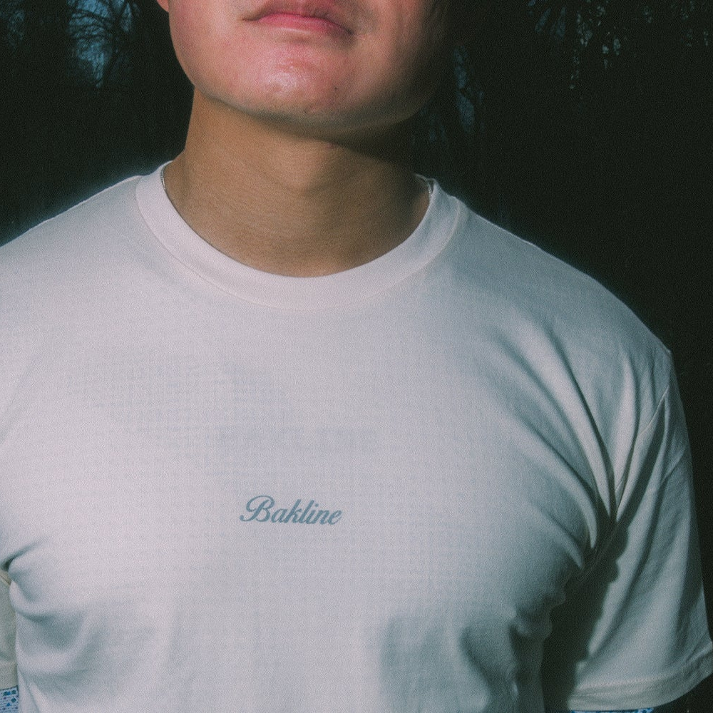 Runner wearing an off white t-shirt with 'Bakline' branding on a trail and Run the city that runs the world on the back.