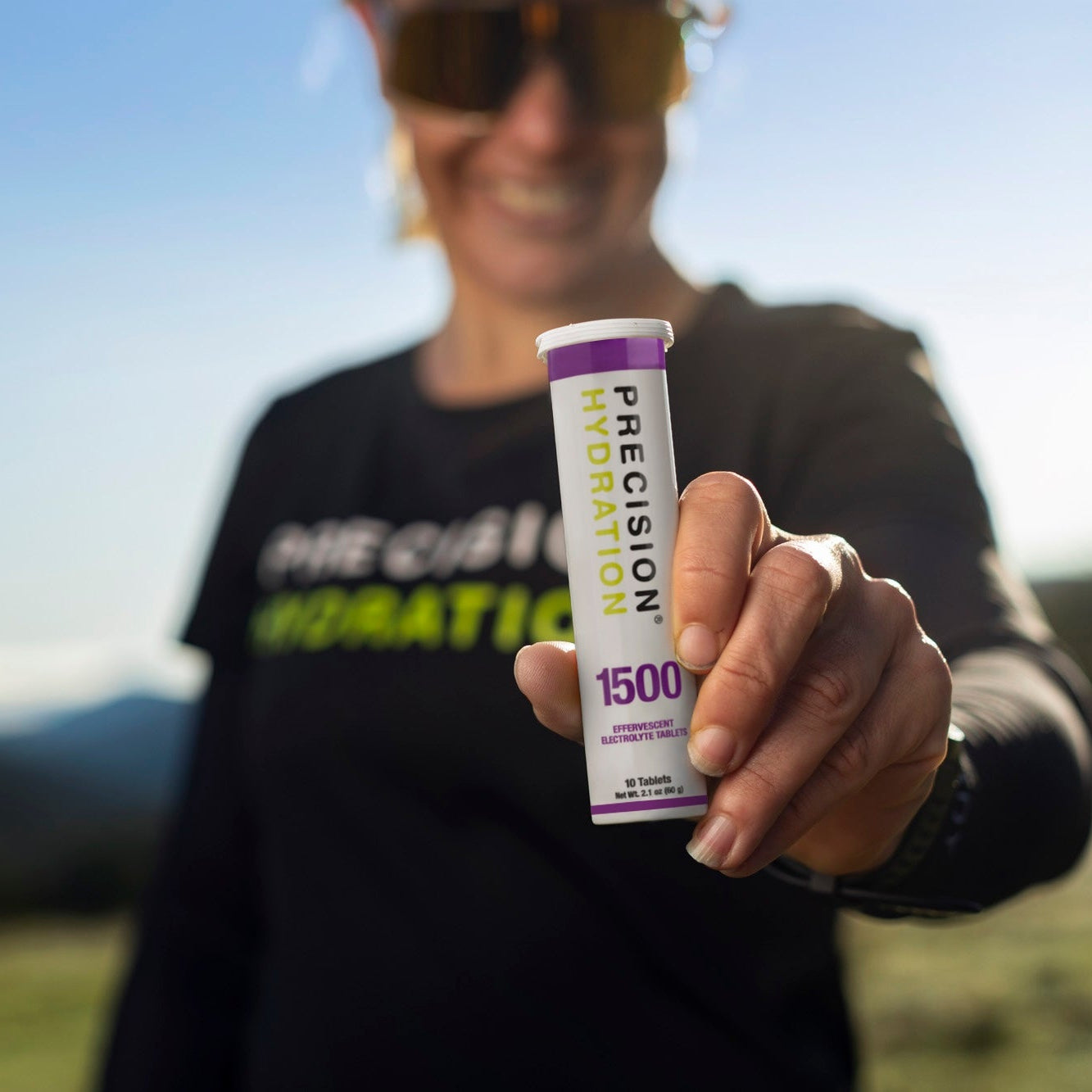 Person holding a Precision Hydration supplement stick pack outdoors