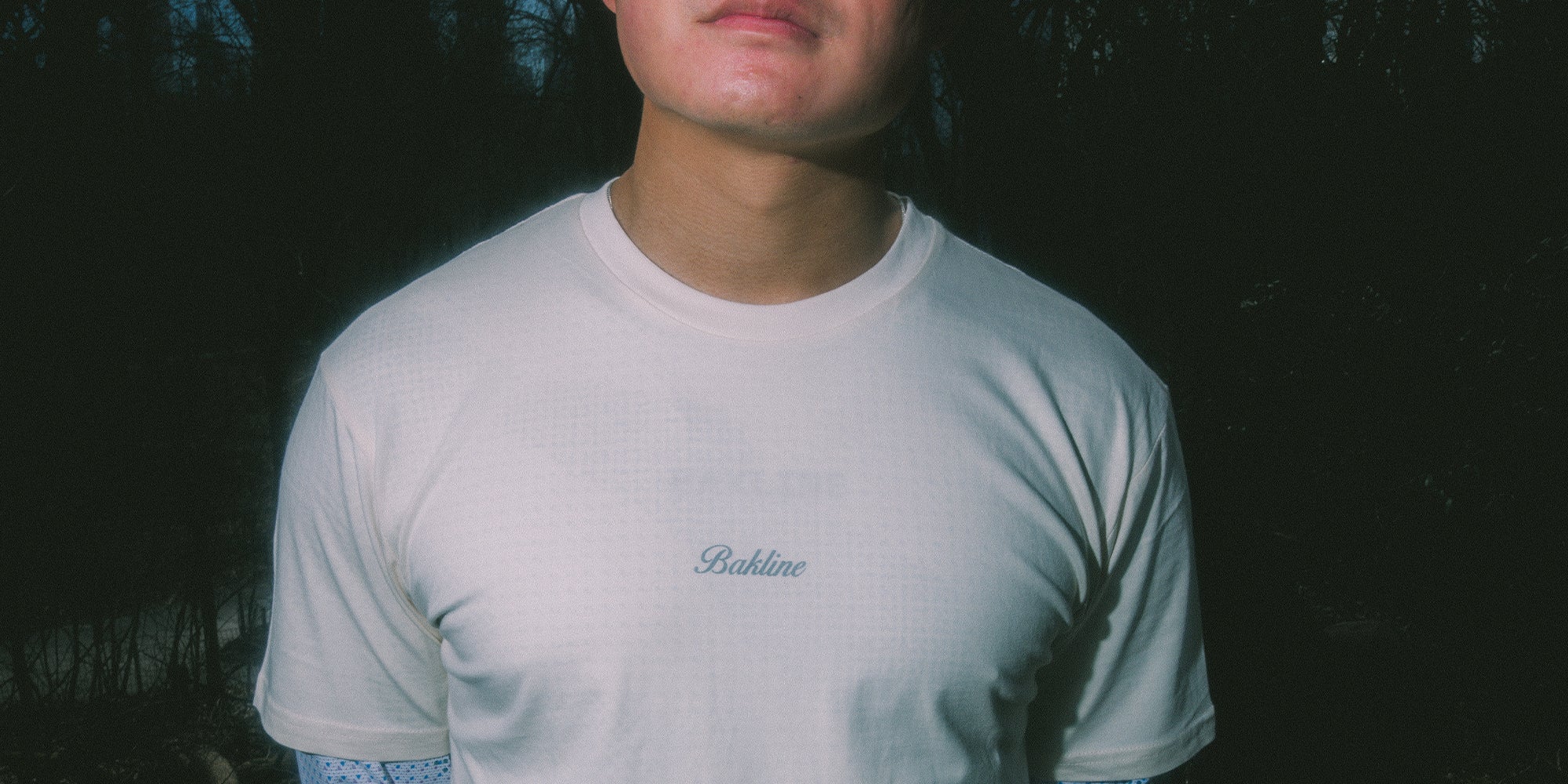 Runner wearing an off white t-shirt with 'Bakline' branding on a trail and Run the city that runs the world on the back.
