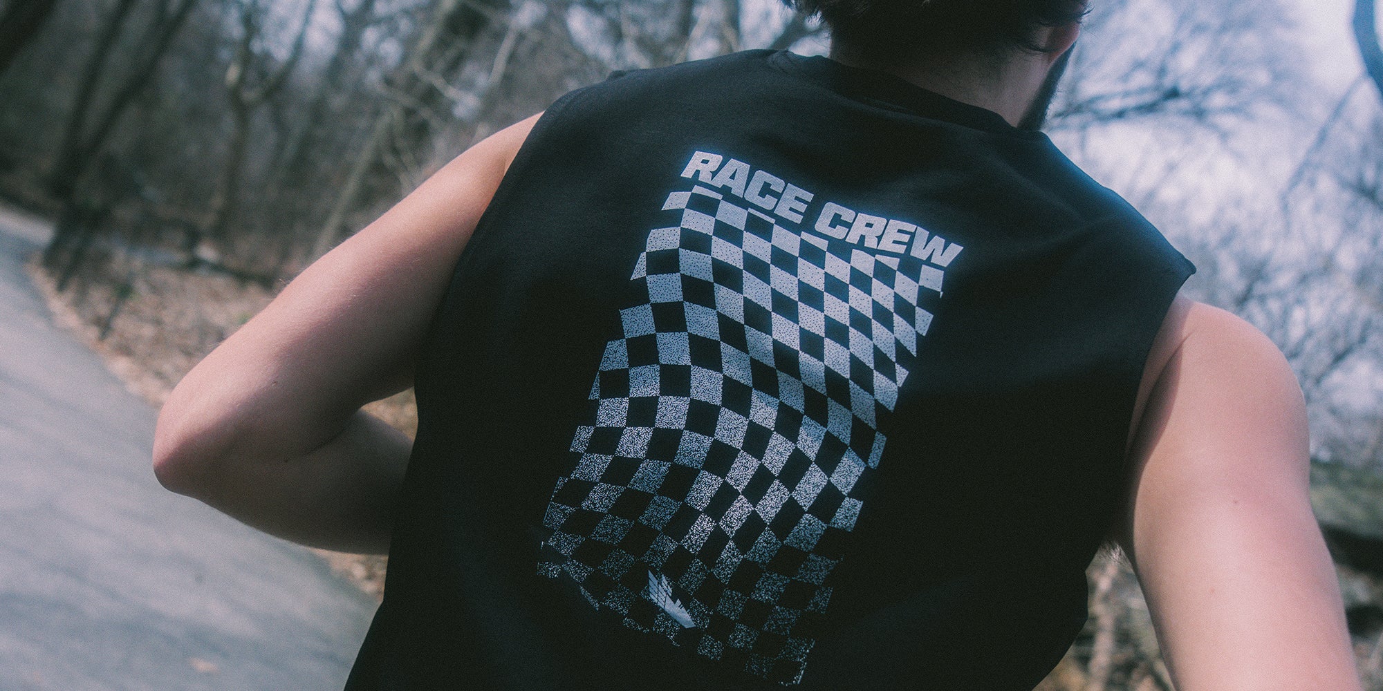 Athlete and runner wearing a black sleeveless tank shirt with 'Race Crew' text and checkered flag Bakline design.