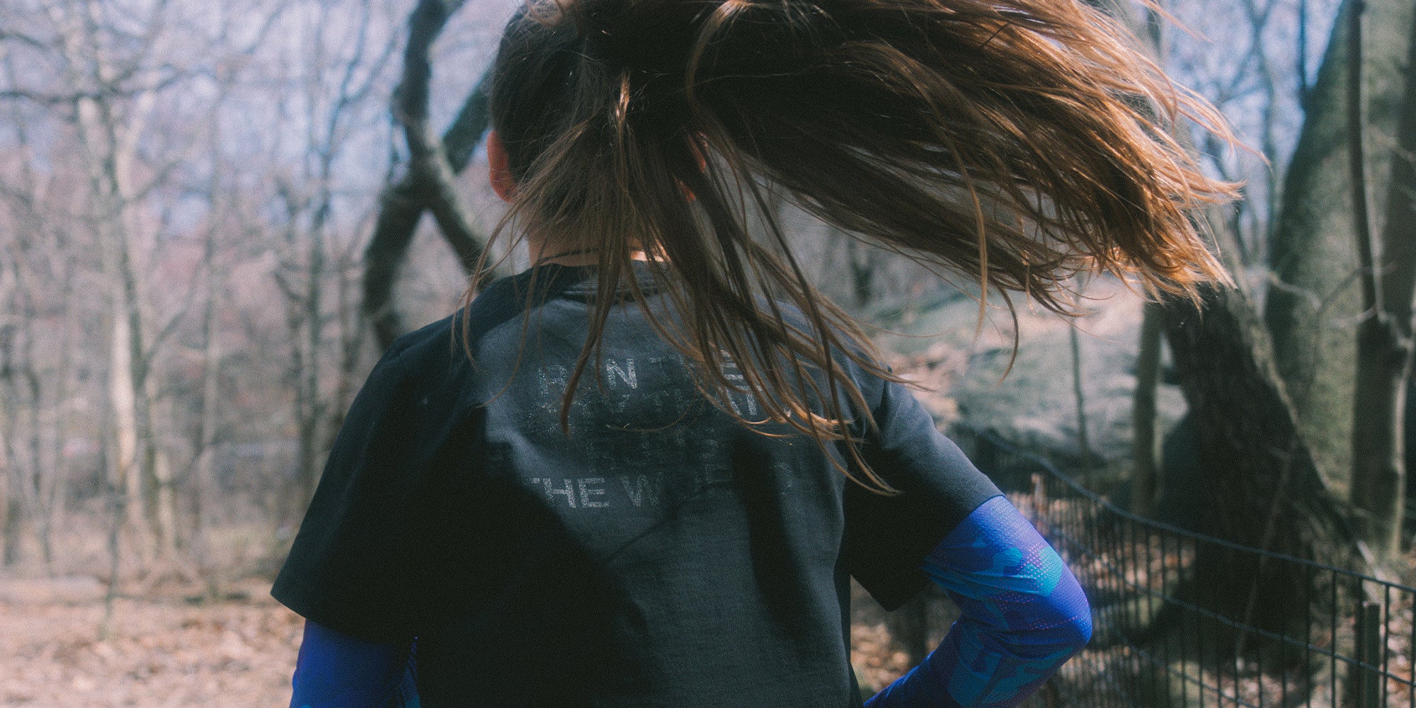 Female Athlete wearing a black top cropped shirt with "Run The City That Runs The world" logo in black, creating a subtle effect.